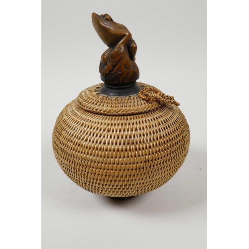 66 - A small Japanese basketwork pot and cover with turned wood pedestal base and carved knop in the form... 