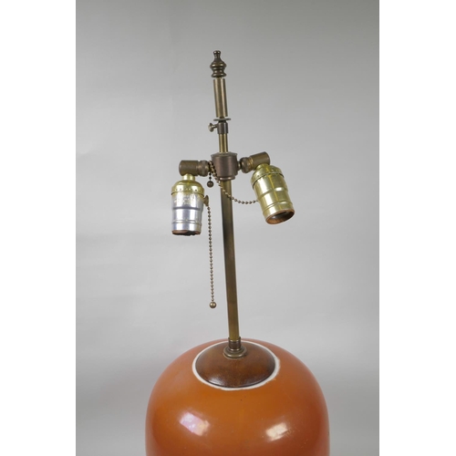 10 - An Oriental coral glazed porcelain lamp with brass fittings on a hardwood base, 26