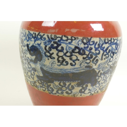 16 - A Chinese porcelain baluster vase with red glaze and blue and white band, decorated with dragons amo... 