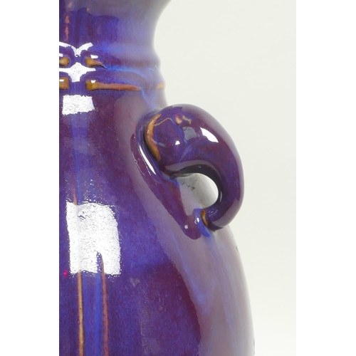 23 - A Chinese amethyst flambe glazed pottery vase with two elephant mask handles, impressed seal mark to... 