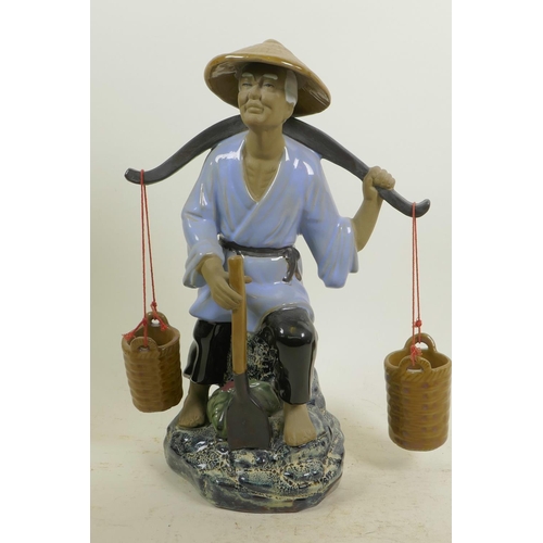 366 - A Chinese, Shiwan style, mud men figure of a workman seated on a rock with his shovel and baskets, 1... 
