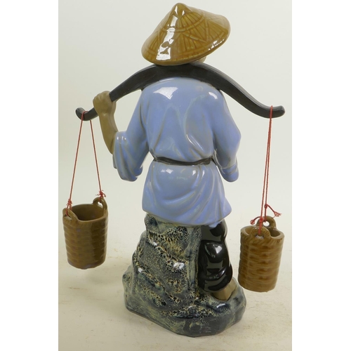 366 - A Chinese, Shiwan style, mud men figure of a workman seated on a rock with his shovel and baskets, 1... 