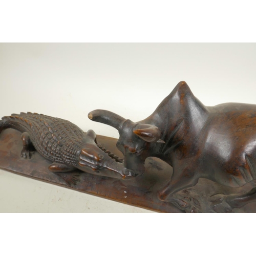 39 - An African carved hardwood figure group decorated with a crocodile attacking a buffalo, 20½