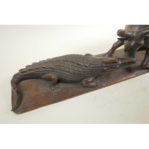 39 - An African carved hardwood figure group decorated with a crocodile attacking a buffalo, 20½