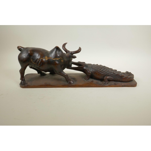 39 - An African carved hardwood figure group decorated with a crocodile attacking a buffalo, 20½