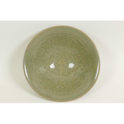 41 - A Chinese porcelain celadon glazed shallow bowl with embossed decoration of birds amongst branches, ... 