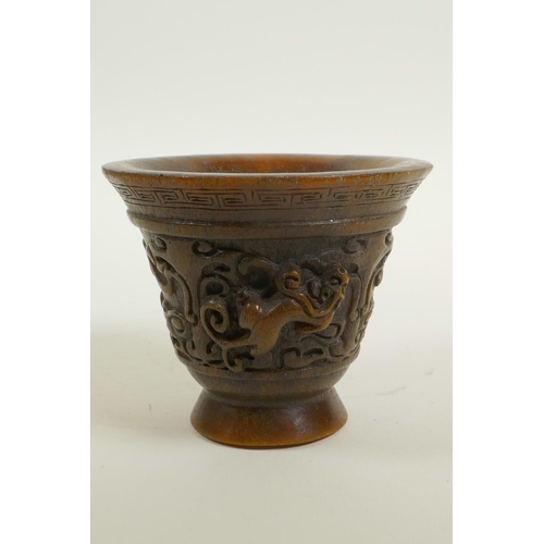 48 - A Chinese faux horn libation cup with two carved handles in the form of a climbing kylin, impressed ... 