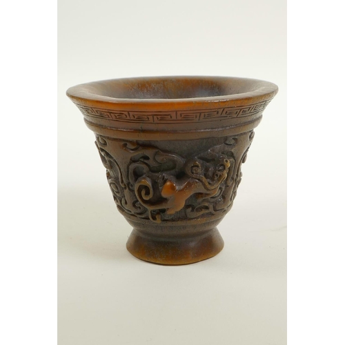 48 - A Chinese faux horn libation cup with two carved handles in the form of a climbing kylin, impressed ... 