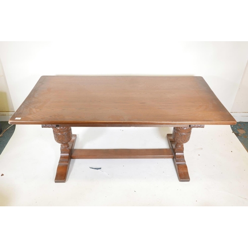 1250 - A plank top oak refectory table with bulbous carved end supports, 66