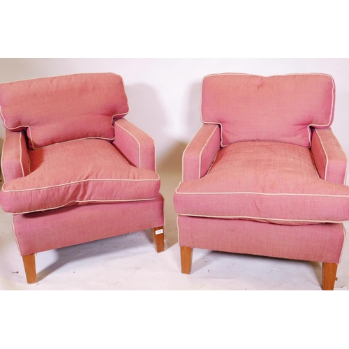 1254 - A pair of deep back contemporary armchairs, raised on tapering supports, each with a footstool, mino... 