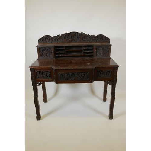 1003 - A Chinese carved hardwood desk, the raised upper section with two small cupboards and pigeon holes, ... 