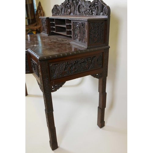 1003 - A Chinese carved hardwood desk, the raised upper section with two small cupboards and pigeon holes, ... 