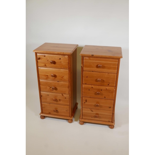 1006 - A pair of pine tallboys with five drawers raised on ball feet, 18