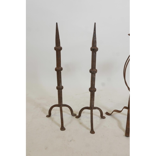 106 - A pair of wrought iron candlesticks on tripod feet, and a pair of similar fire dogs, 22