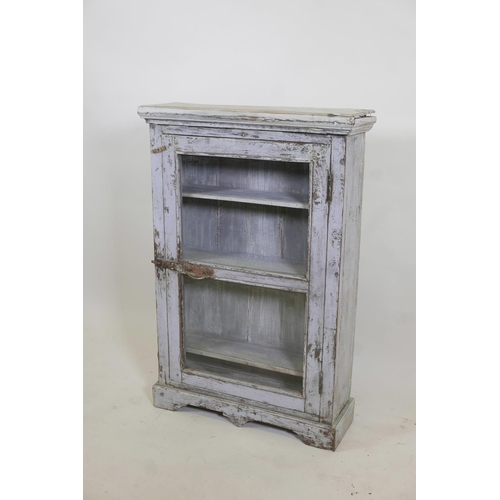 1077 - An Indian painted hardwood cabinet with single glazed door, raised on a shaped plinth, 24