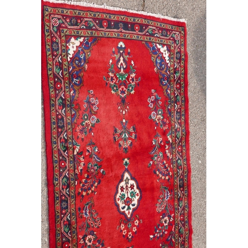 1084 - A Iranian full pile runner with a floral pattern on a rich red ground, 39