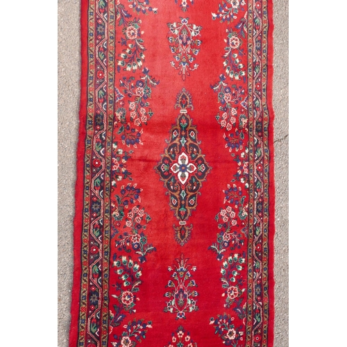 1084 - A Iranian full pile runner with a floral pattern on a rich red ground, 39