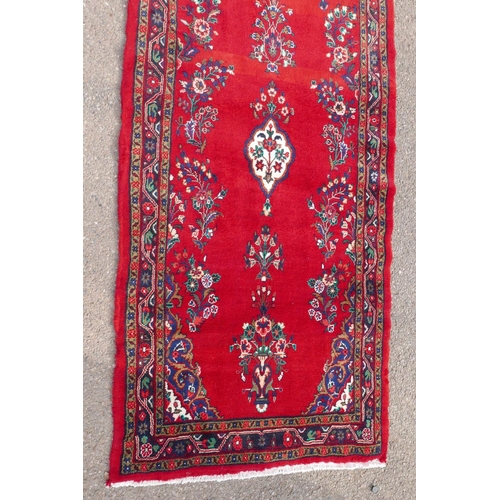 1084 - A Iranian full pile runner with a floral pattern on a rich red ground, 39