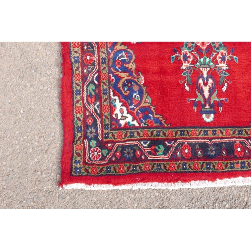 1084 - A Iranian full pile runner with a floral pattern on a rich red ground, 39