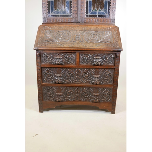 1091 - A C19th oak Arts and Crafts bureau bookcase, with stained glass doors, carved green-man details, the... 