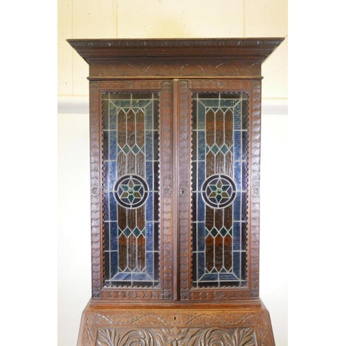 1091 - A C19th oak Arts and Crafts bureau bookcase, with stained glass doors, carved green-man details, the... 