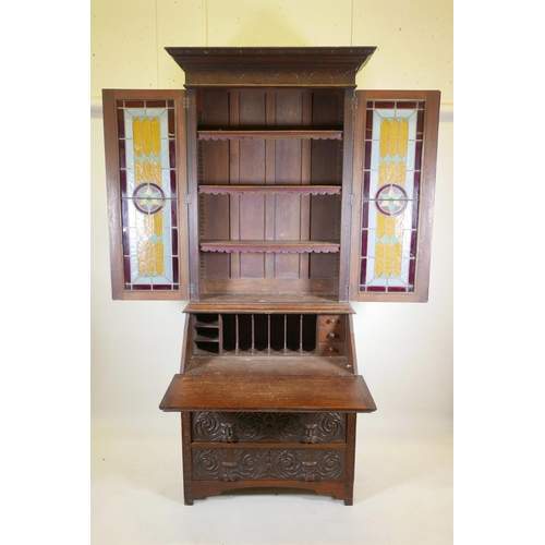 1091 - A C19th oak Arts and Crafts bureau bookcase, with stained glass doors, carved green-man details, the... 