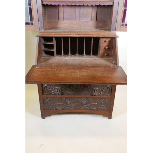 1091 - A C19th oak Arts and Crafts bureau bookcase, with stained glass doors, carved green-man details, the... 