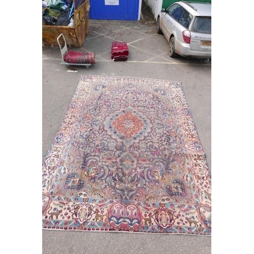 1092 - A vintage Persian Kashmar carpet decorated with a floral medallion on a purple ground, and a cream b... 