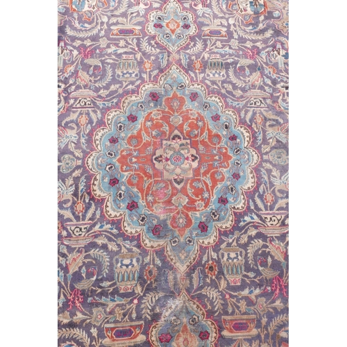 1092 - A vintage Persian Kashmar carpet decorated with a floral medallion on a purple ground, and a cream b... 