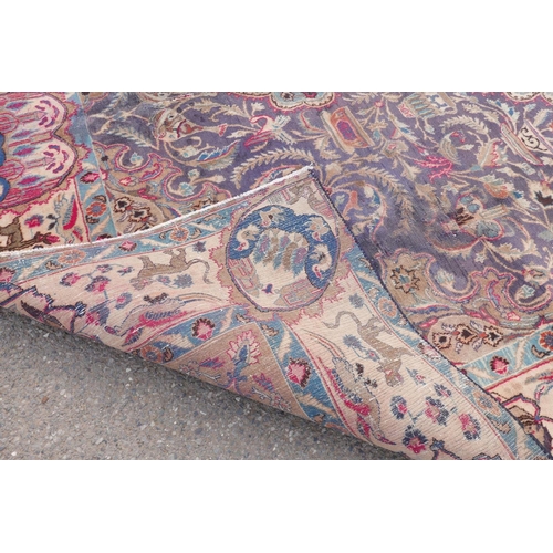 1092 - A vintage Persian Kashmar carpet decorated with a floral medallion on a purple ground, and a cream b... 