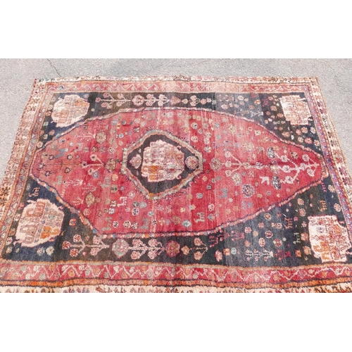 1097 - A Persian heavy pile Kashgai tribal rug with a red medallion design on a black field, 64