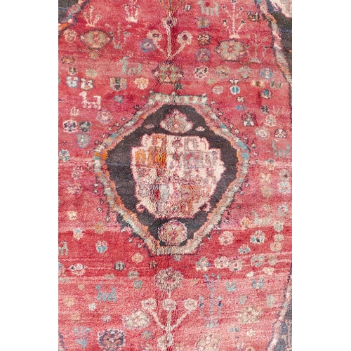 1097 - A Persian heavy pile Kashgai tribal rug with a red medallion design on a black field, 64