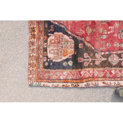 1097 - A Persian heavy pile Kashgai tribal rug with a red medallion design on a black field, 64