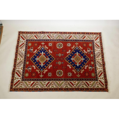 1104 - An Oriental red ground wool rug with twin blue medallion design, 48