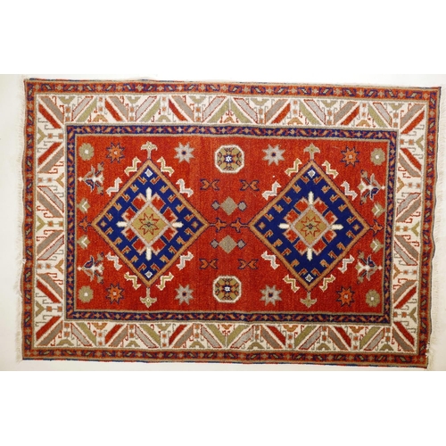 1104 - An Oriental red ground wool rug with twin blue medallion design, 48