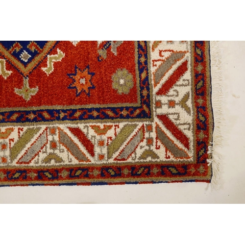 1104 - An Oriental red ground wool rug with twin blue medallion design, 48