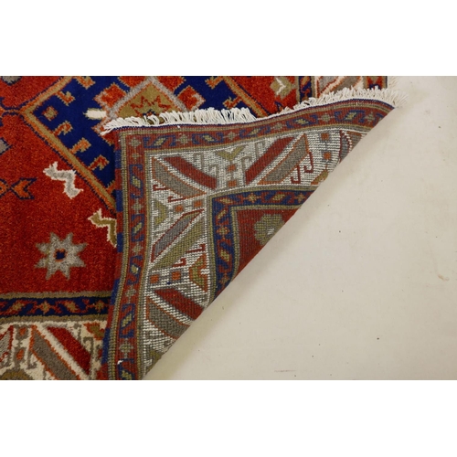 1104 - An Oriental red ground wool rug with twin blue medallion design, 48