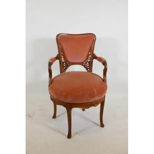 1111 - A C19th Art Nouveau, walnut, tub shaped swivel armchair, with carved and pierced, shaped back, scrol... 