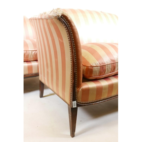 1123 - A pair of two seater settees, with scroll arms and hump backs, raised on reeded tapering supports, A... 