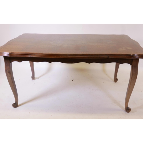 1137 - A French oak drawleaf dining table, with parquetry veneered top and pull out leaves, raised on cabri... 