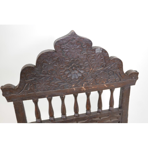 1139 - An antique Indian Pidha chair with a carved and pierced hardwood back, a woven seat, and metal strap... 