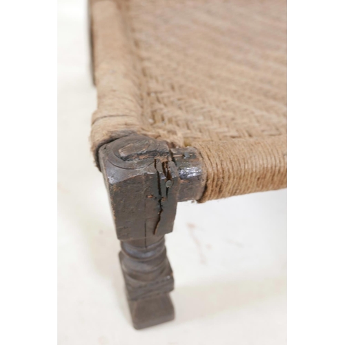 1139 - An antique Indian Pidha chair with a carved and pierced hardwood back, a woven seat, and metal strap... 