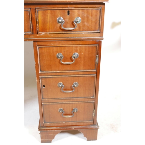 1199 - A mahogany pedestal desk with a tooled inset top, hidden keyboard drawer/slide, drawers and a cupboa... 