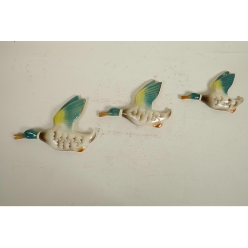 120 - A set of thee 1940s Keele Street Pottery graduated flying wall ducks, hand painted and glazed plaque... 