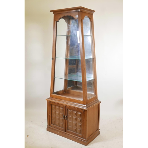 1201 - An American light oak display cabinet of tapering form, with mirrored back and single door over two ... 