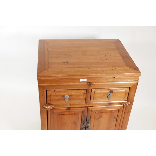 1210 - A Chinese fruitwood cupboard with two drawers over two doors, 25