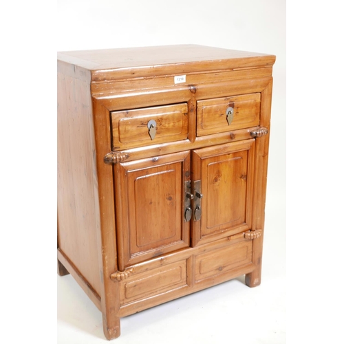 1210 - A Chinese fruitwood cupboard with two drawers over two doors, 25