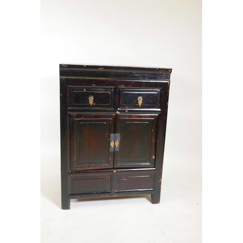 1211 - A Chinese varnished fruitwood cupboard with two drawers over two doors, 25