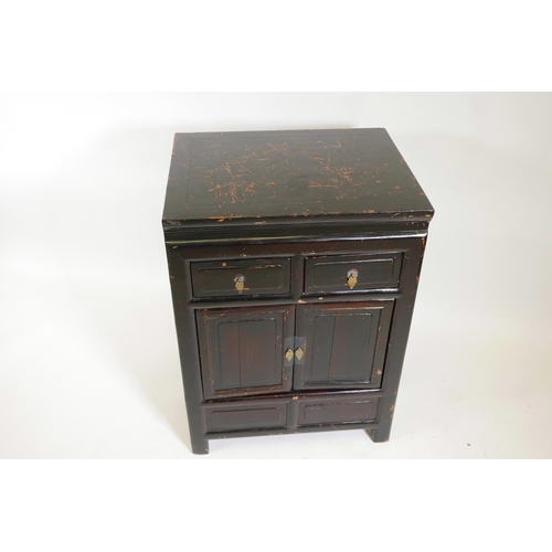 1211 - A Chinese varnished fruitwood cupboard with two drawers over two doors, 25