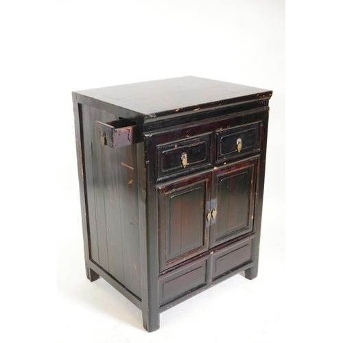 1211 - A Chinese varnished fruitwood cupboard with two drawers over two doors, 25